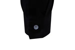 Detailed close-up of a men's black cotton linen shirt cuff with a single translucent button