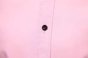 Close-up detail of a pink men's casual shirt showing the button and fabric texture