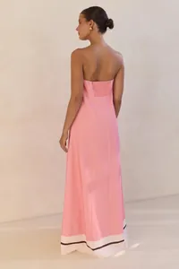 Back view of a strapless pink maxi dress with a striped white hem and smocked back detail.