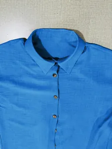 Close-up detail of a bright blue casual long-sleeved button-down shirt with wooden buttons