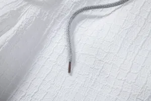 Macro close-up showing white jacquard fabric texture and grey braided drawstring detail
