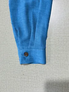 Detailed view of the bright blue shirt sleeve cuff featuring a natural brown button.