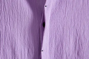 Detail shot of purple seersucker textured fabric and buttons on men's summer shirt.