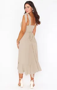 Detailed back view of an elegant beige sleeveless dress with tie straps and ruffled hem