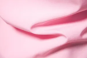 Macro close-up view of soft pink solid color fabric texture for men's casual shirt