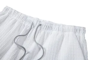 Close-up of white jacquard shorts with elastic waistband and grey drawstring detail.