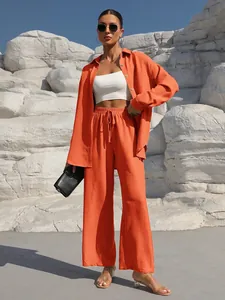 Detailed view of vibrant orange two-piece set with long-sleeve shirt and wide-leg trousers.