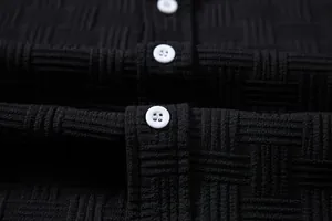Detailed close-up of black textured fabric and white buttons on a men's summer shirt.