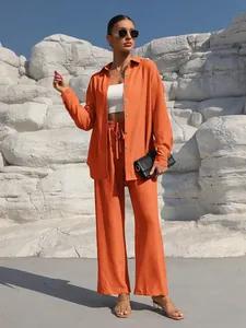 Detailed view of women's orange long-sleeve shirt and matching wide-leg trousers set