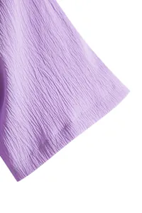 Close-up macro view of lavender purple crinkle fabric texture on a men's shirt sleeve.