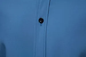 Close-up detail of navy blue casual long-sleeve shirt with black button and fine stitching.