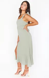 Elegant sage green midi dress with shoulder ties, side slit and ruffle hem details.