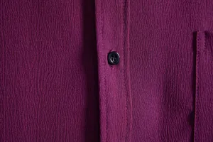 Close-up detail of textured fabric and button on men's purple casual short sleeve shirt