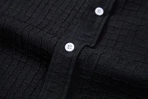 Macro detail of black jacquard fabric texture and white buttons on a men's shirt