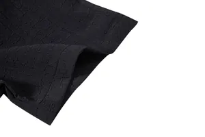 Detailed macro view showing the textured black jacquard fabric of a men's summer shirt