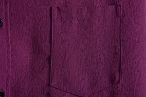 Close-up macro detail of men's purple casual shirt showing textured fabric and chest pocket