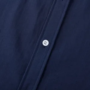 Makroansicht der marineblauen Leinenhemd-Stofftextur und des weißen Knopfdetails