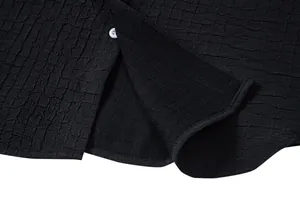 Close-up detail of black textured jacquard fabric and button on men's summer shirt
