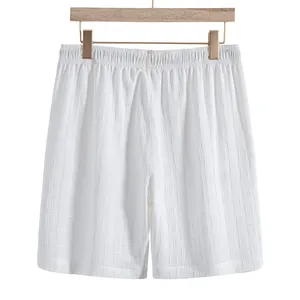 Close-up of white textured summer shorts with elastic waistband on a wooden hanger.