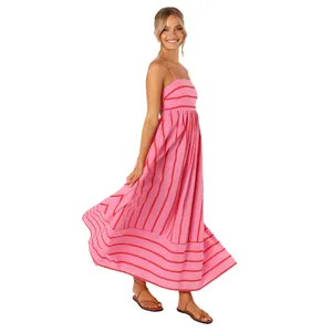 Side view of a pink striped spaghetti strap backless maxi dress worn by a smiling model.