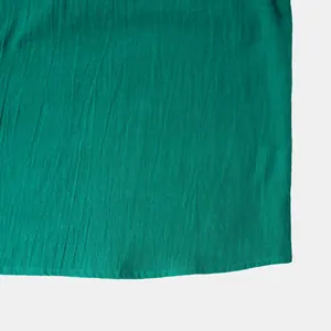 Close-up of green cotton linen shirt fabric showing breathable texture and hem