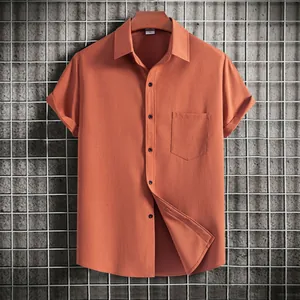 Close-up of terracotta men's short sleeve shirt showing textured fabric and pocket detail.