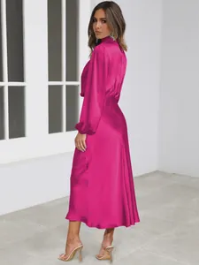 Side profile view of an elegant fuchsia pink satin long sleeve evening midi dress