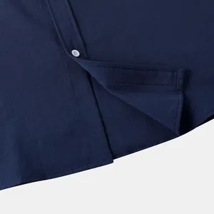 Detailaufnahme des Saums eines marineblauen Leinenhemdes mit Knopf