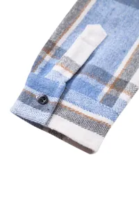 Primer plano detallado de un puño de camisa de franela a cuadros azules y blancos con botón negro