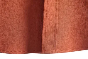 Detailed macro view of rust orange men's shirt fabric showing fine stitching and texture.