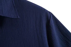 Close-up detail of the textured navy blue fabric and shoulder seam on men's shirt.
