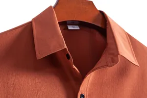 Close-up of rust brown textured fabric on a men's casual lapel shirt with black buttons