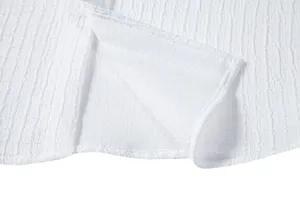 Close-up detail of white textured jacquard fabric showing hem and stitching