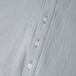 Close-up view of fabric texture and white buttons on a grey casual linen shirt for men.