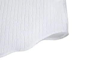 Close-up detail of the textured jacquard fabric and curved hem of a white casual shirt.