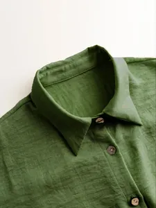 Macro close-up of green linen texture shirt collar with decorative wooden buttons
