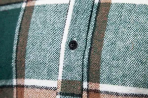 Primer plano de una camisa a cuadros verde y marrón con textura de tela y botón