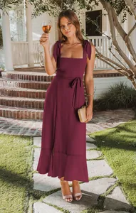 Elegant burgundy midi dress featuring tie-shoulder straps and ruffled split hem detail.