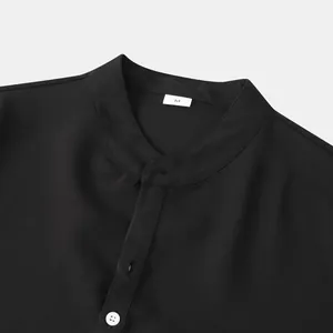 Vista detallada del cuello mao y la tapeta de botones de una camisa negra para hombre
