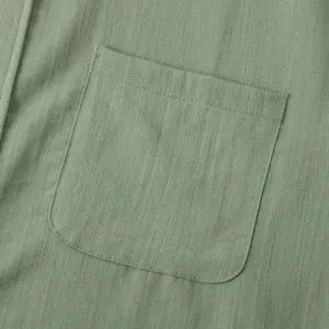 Makroansicht der Brusttasche an einem salbeigrünen Leinenhemd für Herren mit feinen Nähten