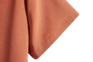 Close-up of the terracotta textured fabric and sleeve stitching on a men's casual shirt.