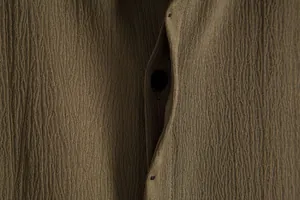 Close-up detail showing the olive brown crinkled texture of a men's summer shirt
