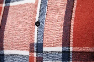 Primer plano de tela de franela a cuadros roja y azul con tejido de espiga y botón.