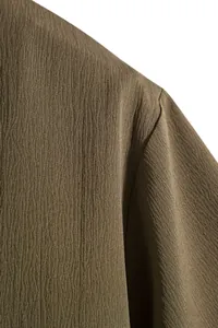 Close-up of the crinkled fabric texture on a men's loose-fit summer short-sleeved shirt