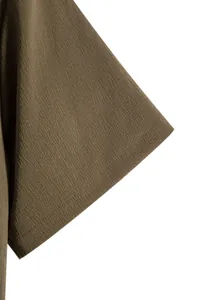 Macro view of textured olive green fabric and hem stitching of men's short-sleeve shirt