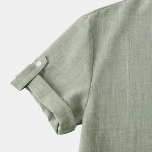 Detalle de manga de camisa de manga corta con trabilla en tejido texturizado verde salvia.