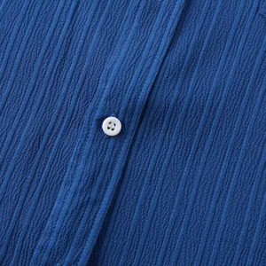 Primer plano de tela azul con textura de camisa para hombre y botón blanco