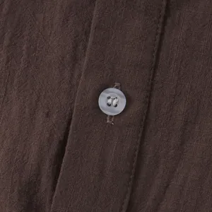 Close-up detail of brown cotton linen shirt fabric featuring a single translucent button.