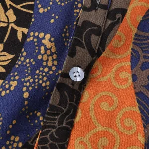 Detailed view of men's Hawaiian shirt fabric with colorful patchwork and button