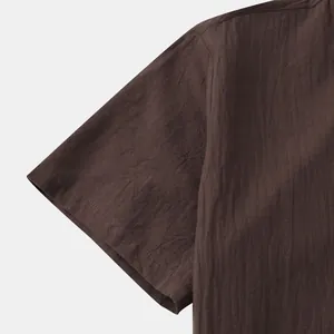 Close-up detail of dark brown cotton-linen men's shirt showing fabric texture and sleeve